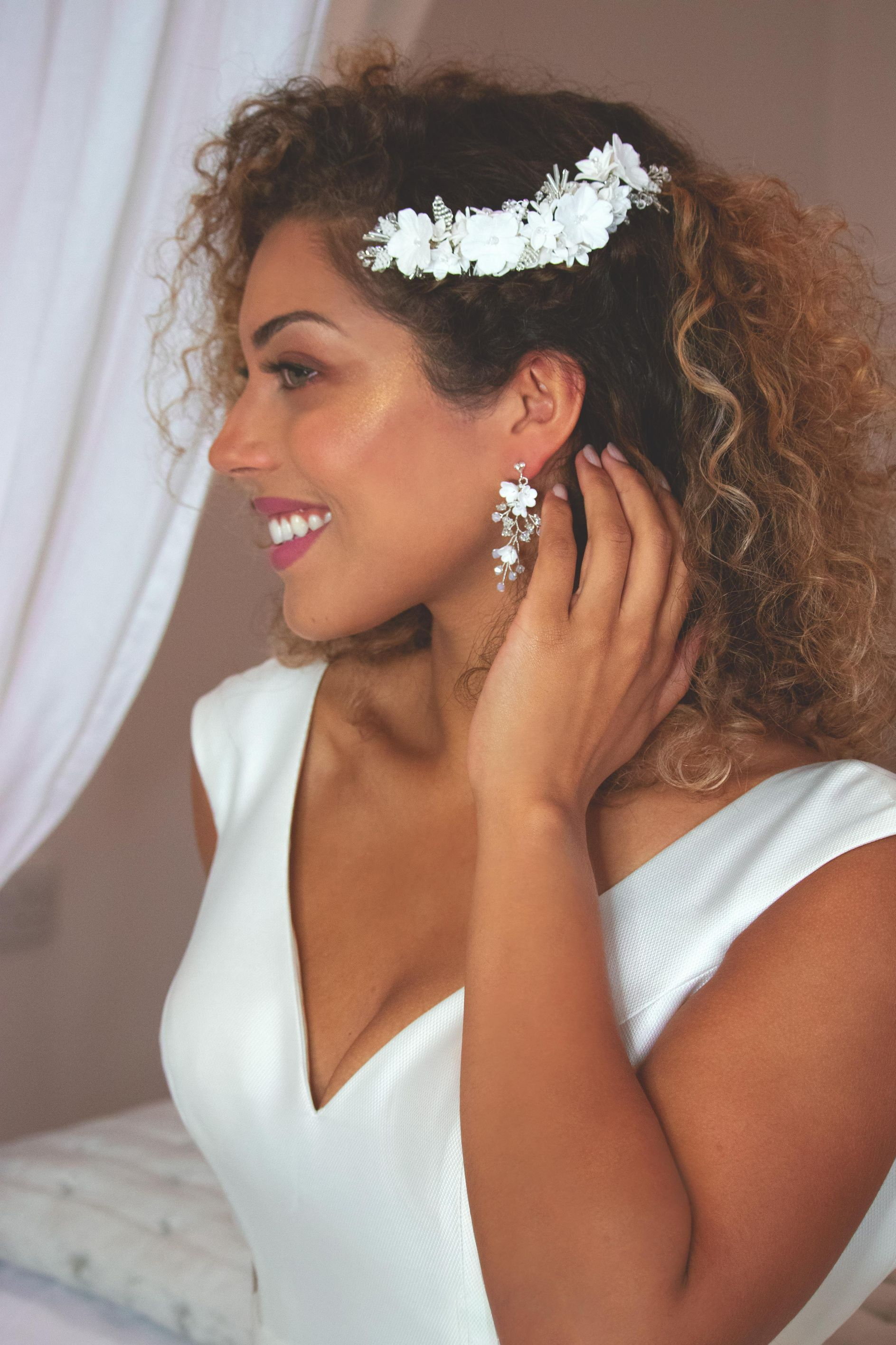 Mixed raced bride in white dress smiling with hand to her ear