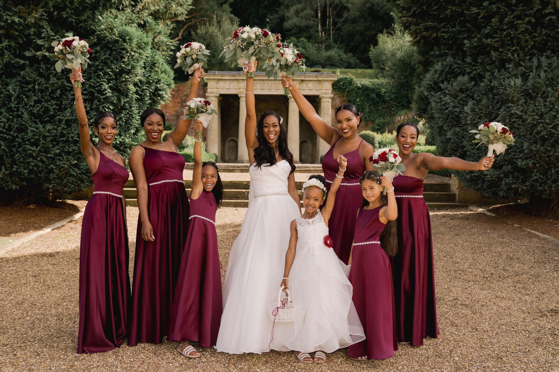 Black bride and bridesmaids in deep red dresses holding up bouquets