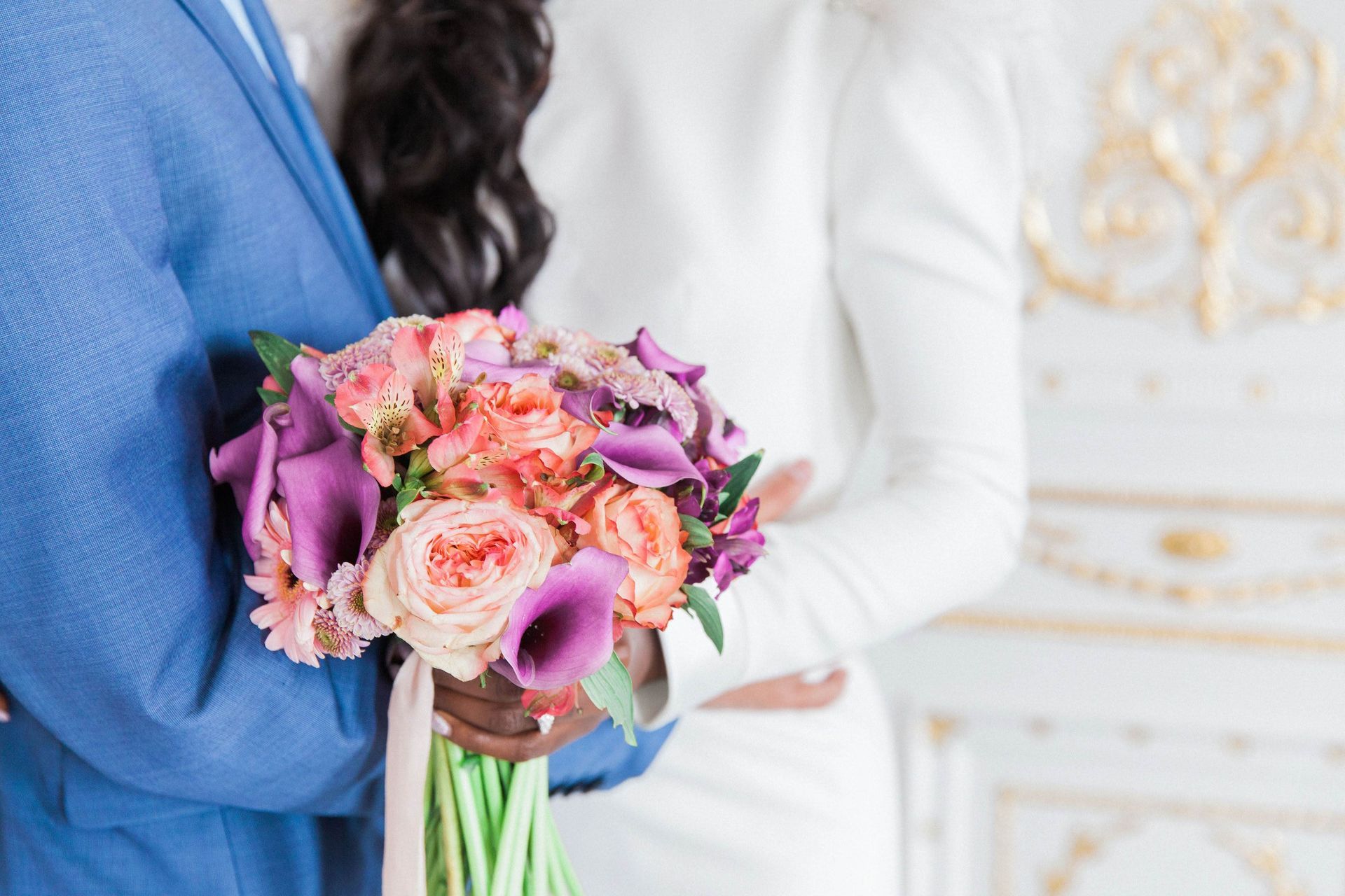 Close up of peach and purple bridal bouquet been held in hands of a black bride