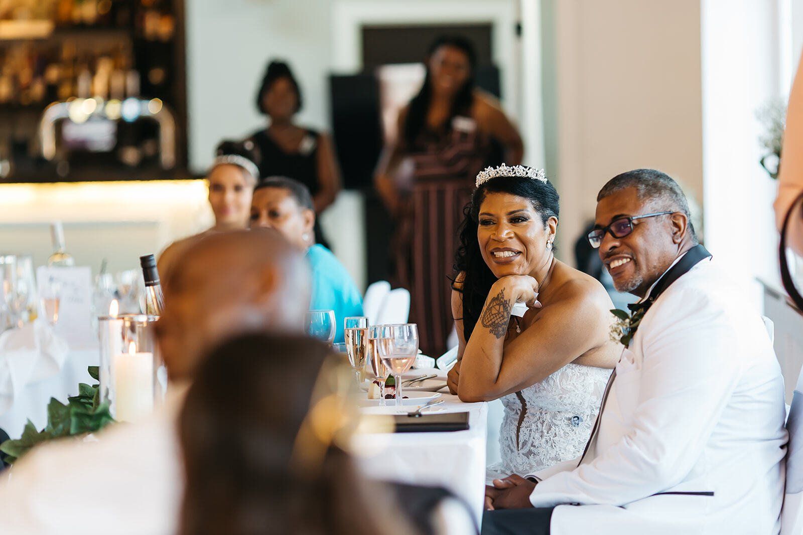 Black bride and groom seated and smiling at wedding reception