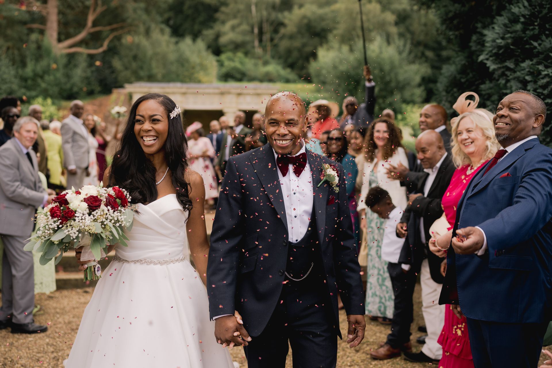 Black bride and groom holding hands and walking through confetti