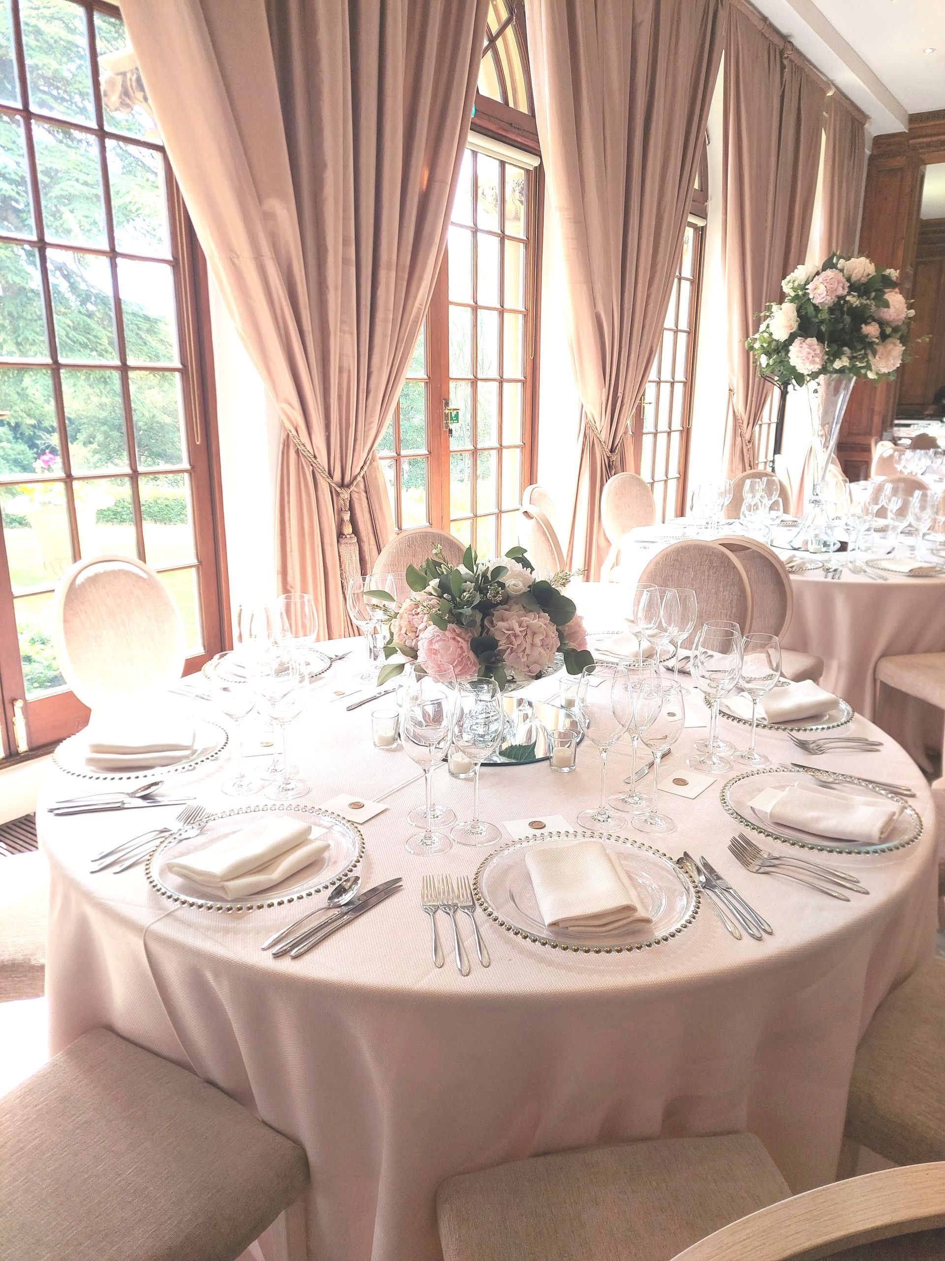 Round wedding table with light pink tablecloth by a window