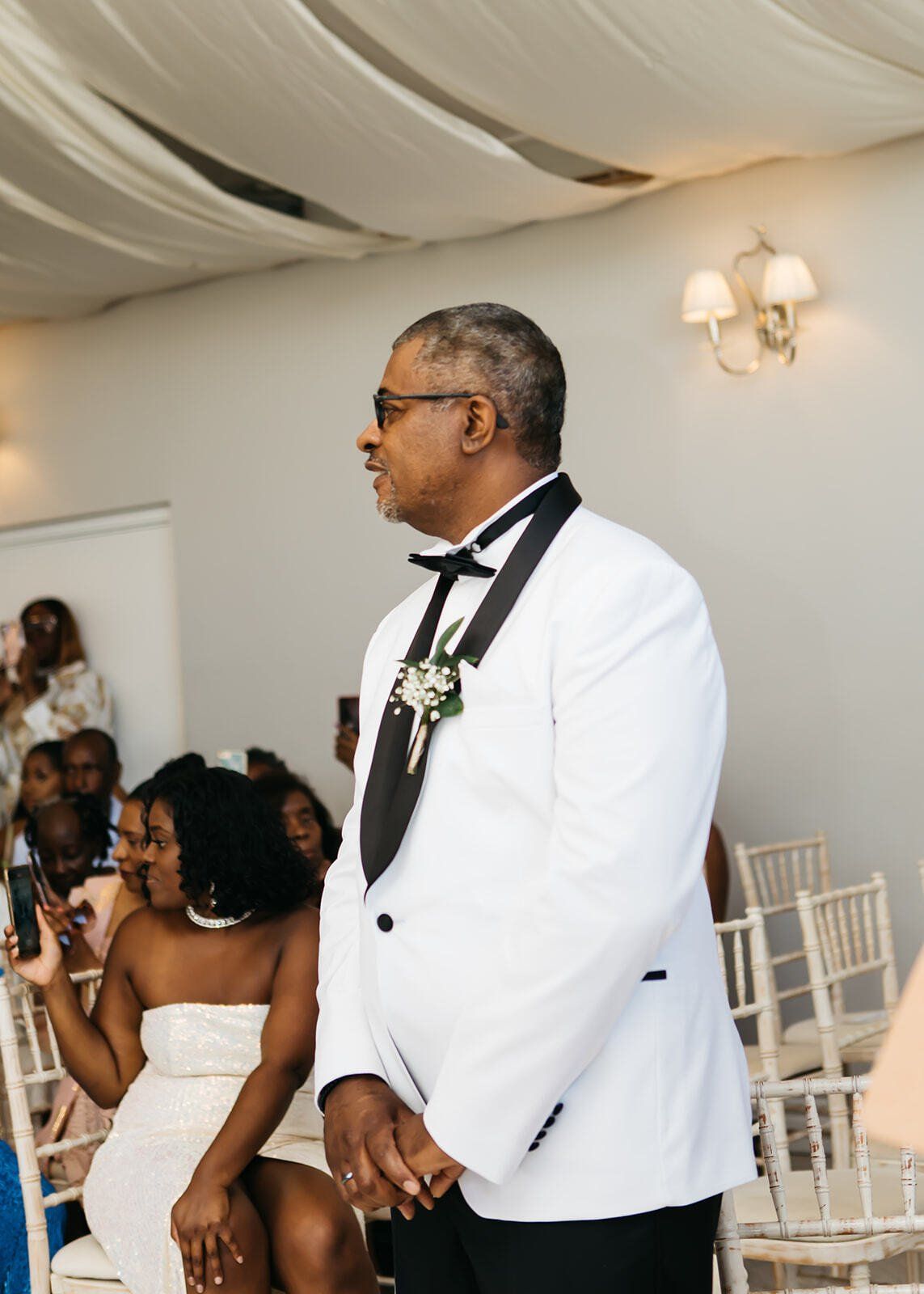 Black groom waiting at ceremony aisle