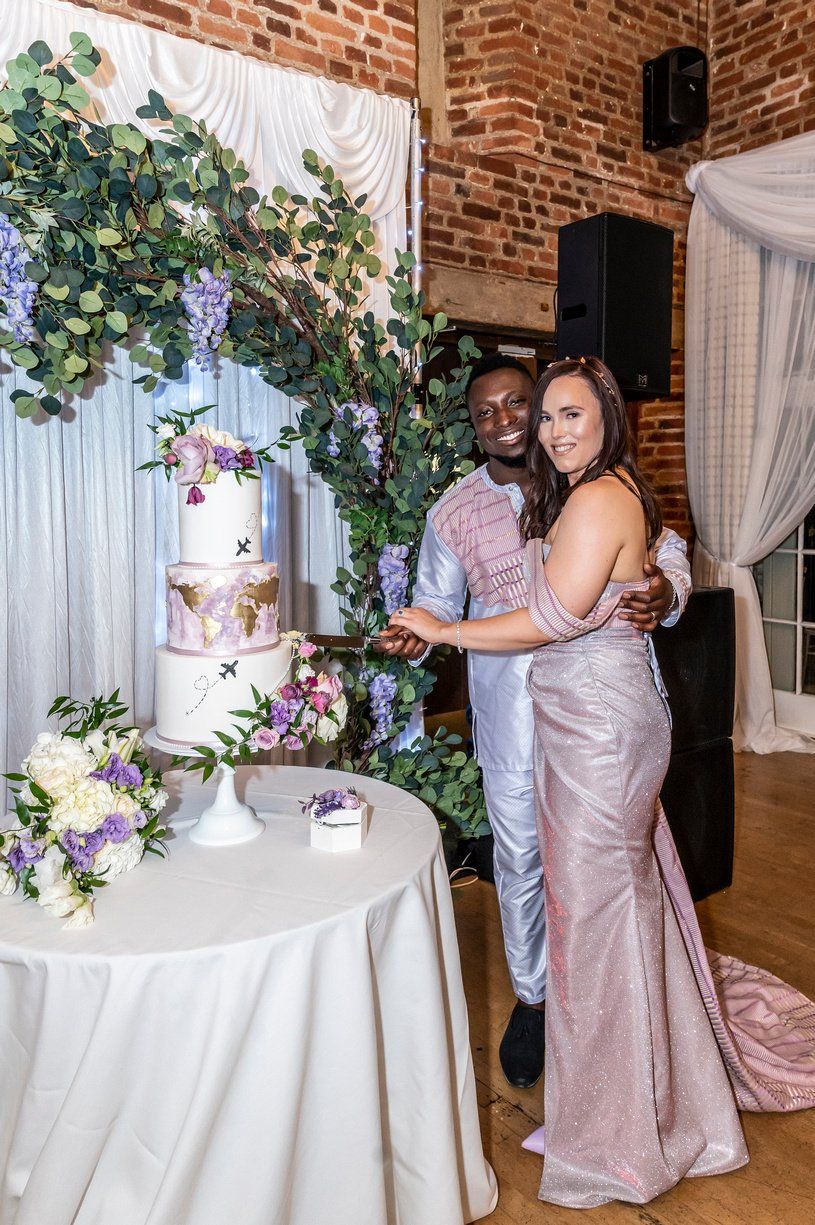 Bride and groom smiling at camera cutting wedding cake