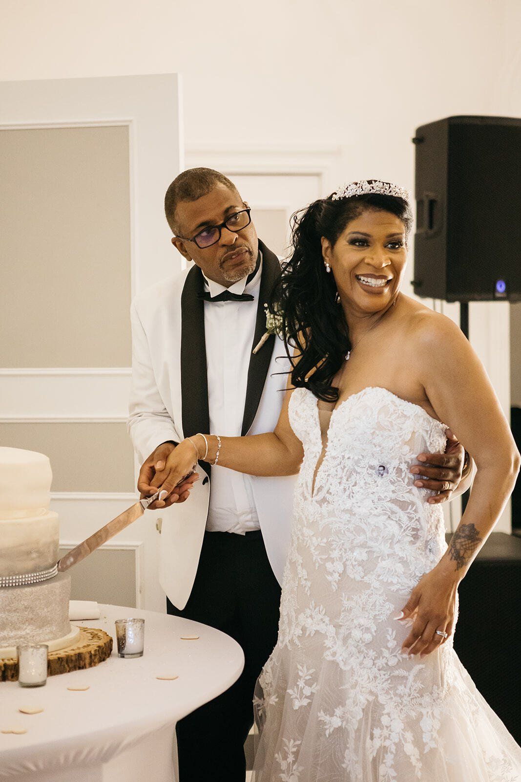 Black bride and groom cutting wedding cake and smiling