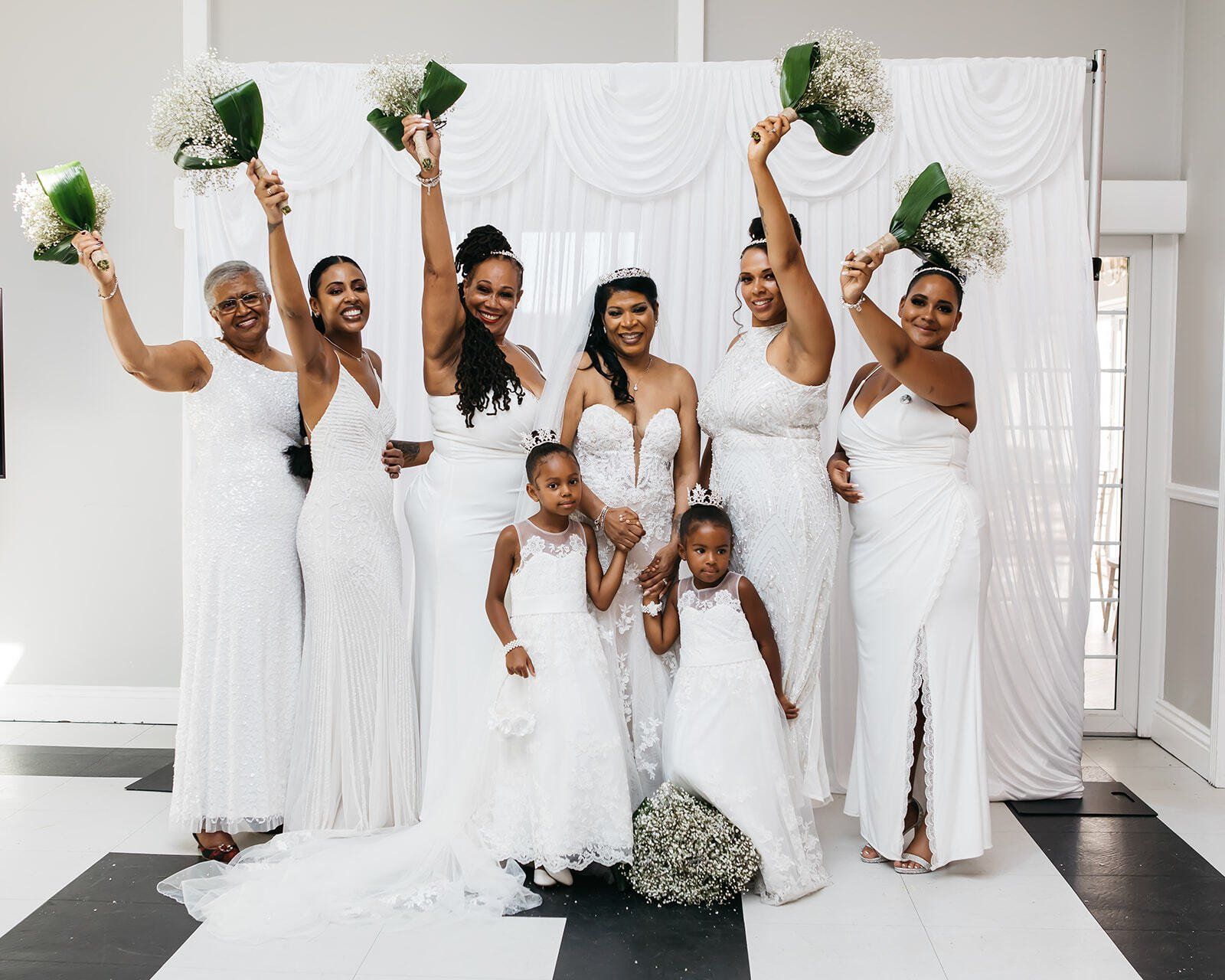 Black bridesmaids and flower girls standing dressed in white