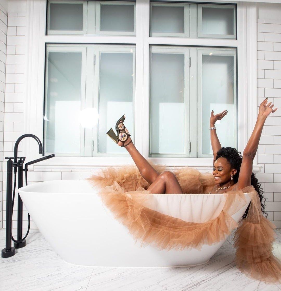 Black bride in wedding dress celebrating in the bath