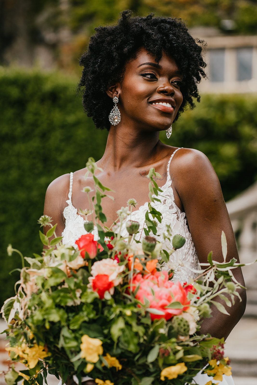 Black bride smiling and holding colourful orange, green and yellow bridal bouquet