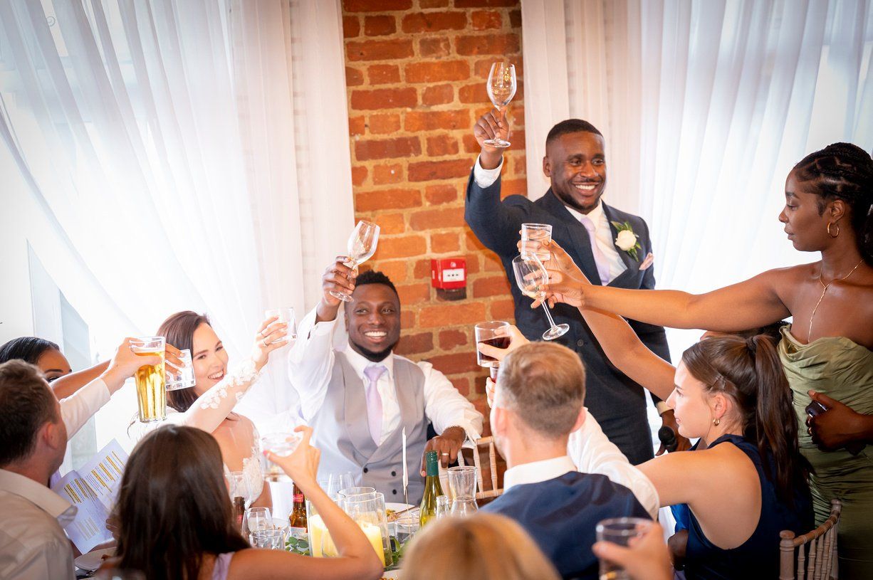 Black groom and best man seated and raising glasses for a toast