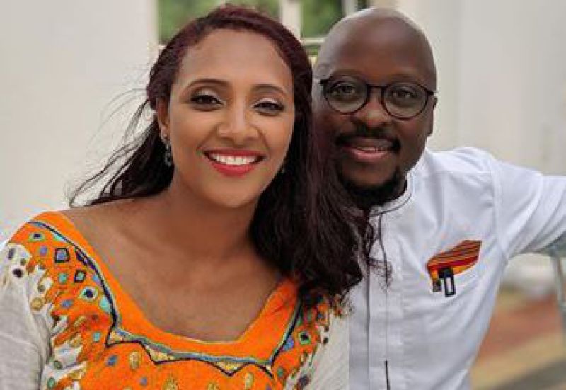 Black couple in traditional dress smiling at camera