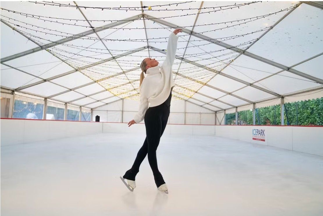 Professional young girl skater striking a beautiful pose in ice skates on an ice rink