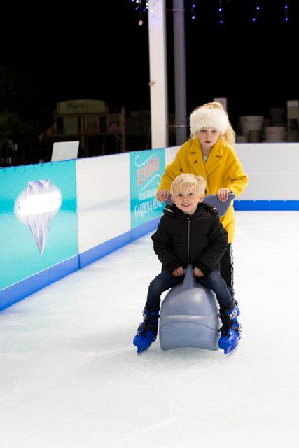 Young girl with ice skating with skate aid