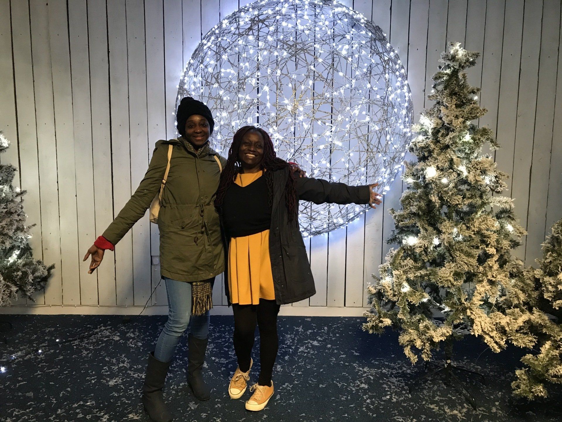 Two ice rink customers posing for a photo with Christmas Tre