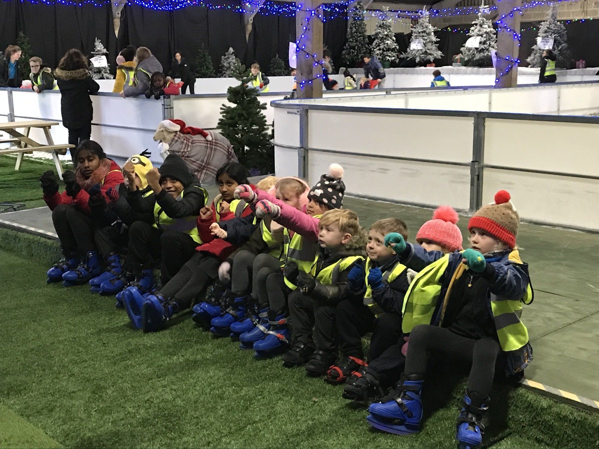 Group of children wearing ice skates being taught about skating before trying themselves