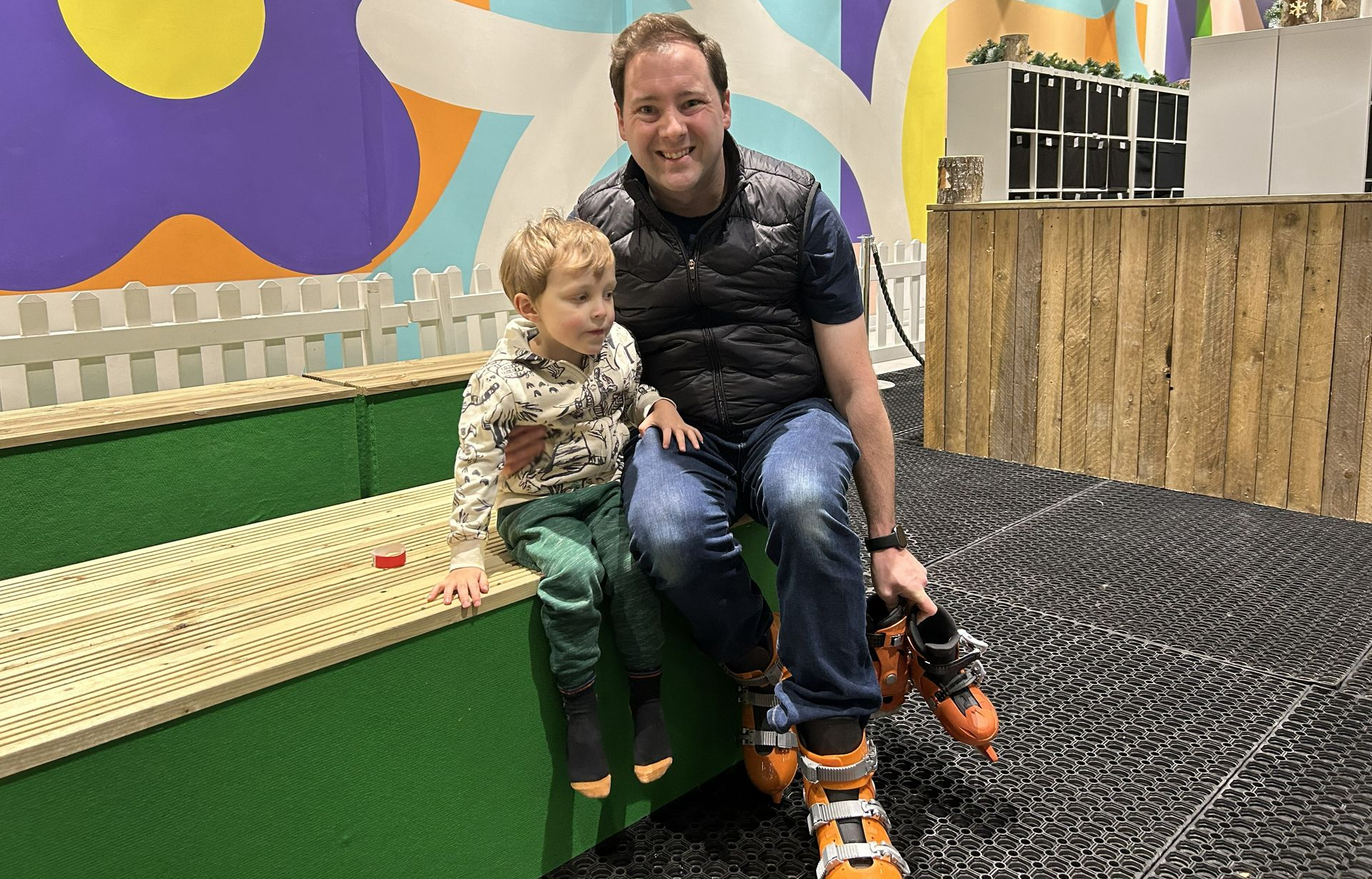 Dad and boy getting putting on orange boots for ice skating