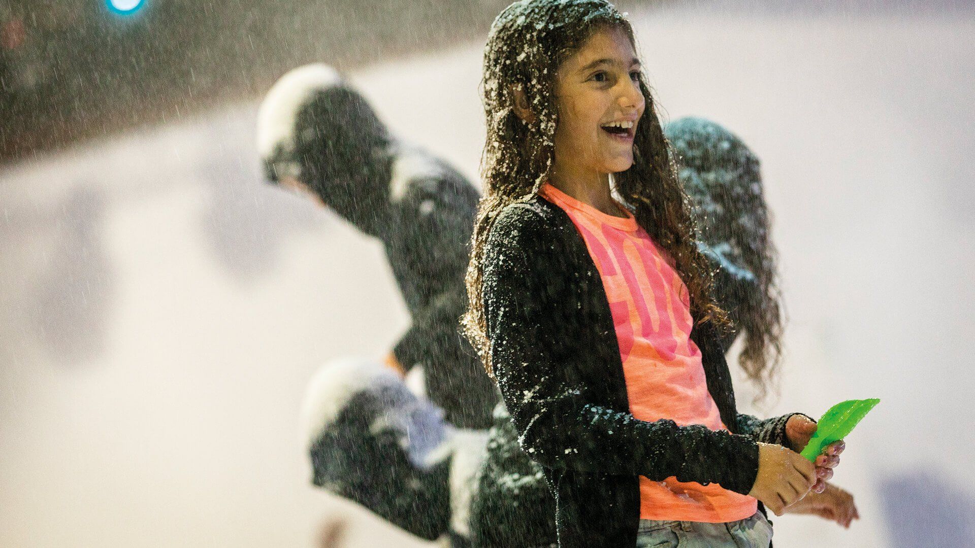 Young girl with broad smile with snow falling on her hair