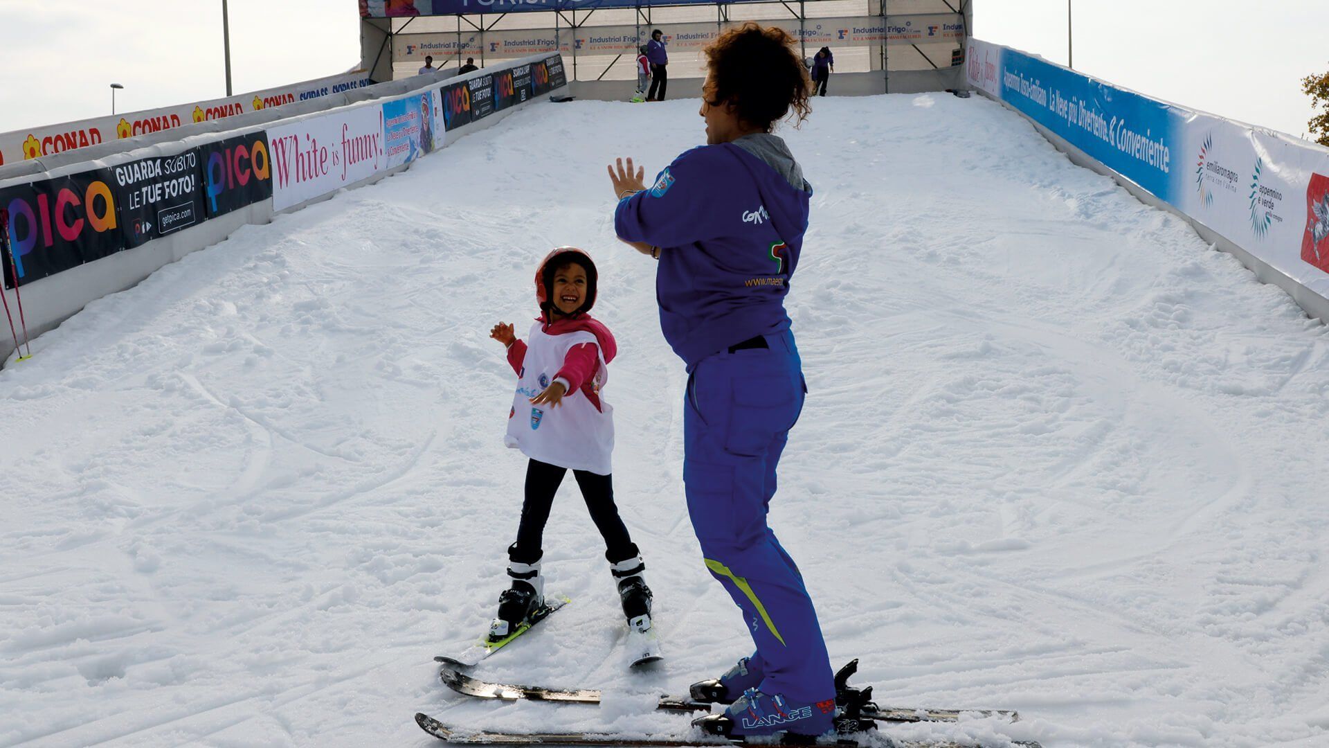 Outdoor snow slope with adult and child on skis