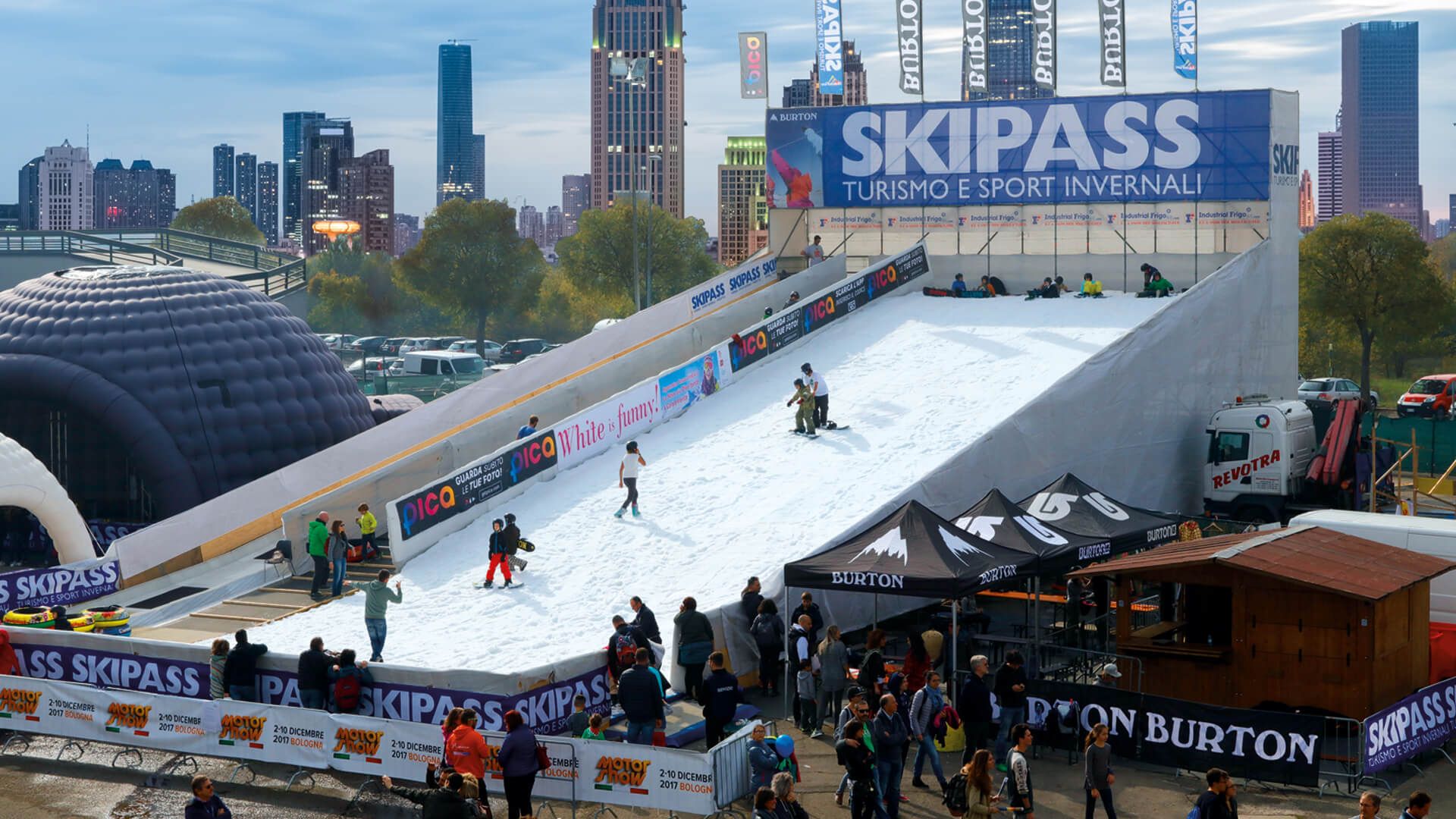 Outdoor snow slope with people skiing and snowboarding down