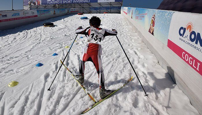 Outdoor snow slope with child making his way up the slope on skis and with poles