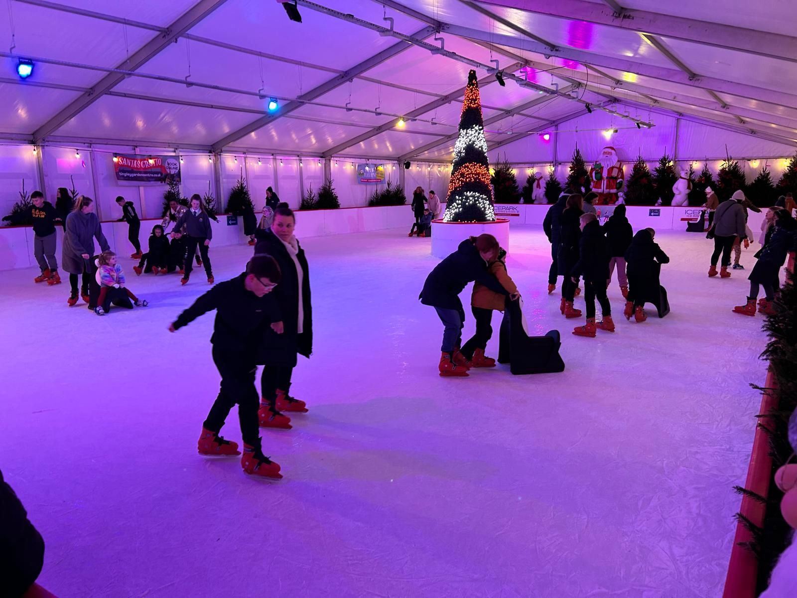 Ice Skating Rink with ice skaters, fully decorated with purple back lighting