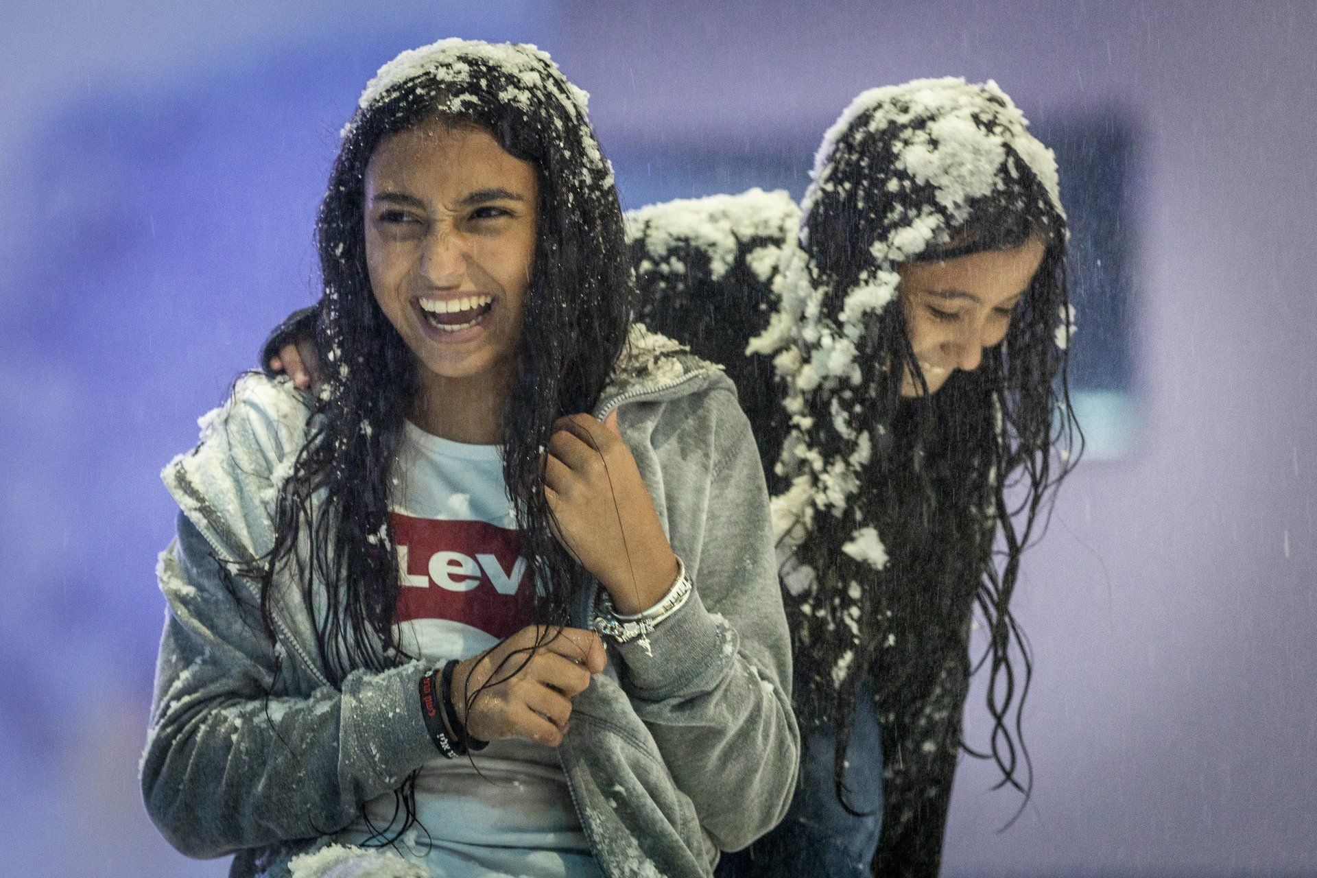 Two young girls with huge smiles playing in snow playground