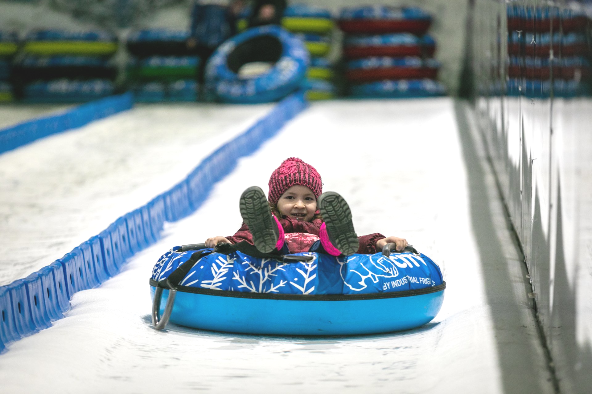 Blue inflatable rink with smiling toddler sliding down and ice slide