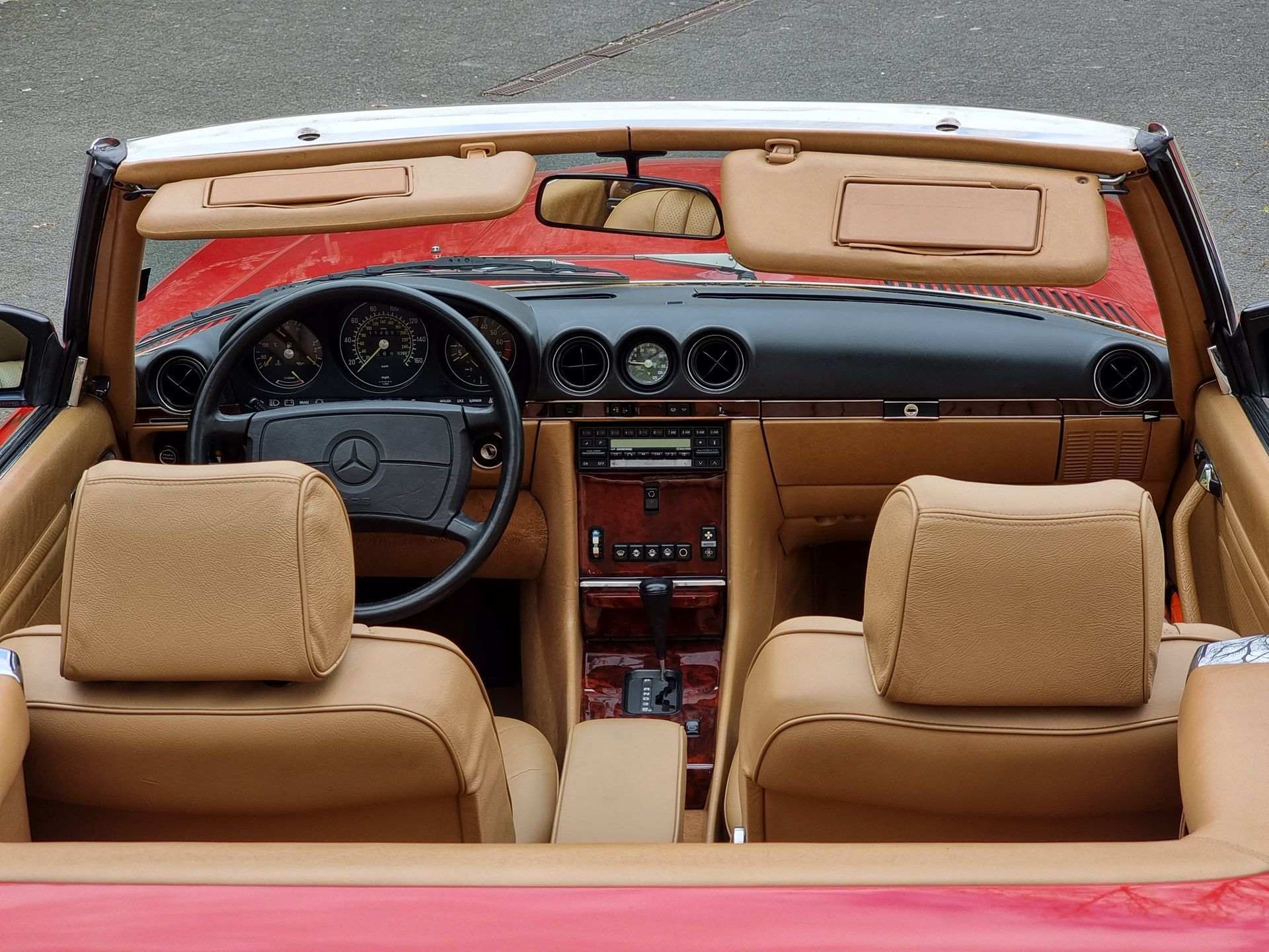 Mercedes Benz R107 Innenraum mit beigem Leder und Holzapplikationen. Außenfarbe rot.