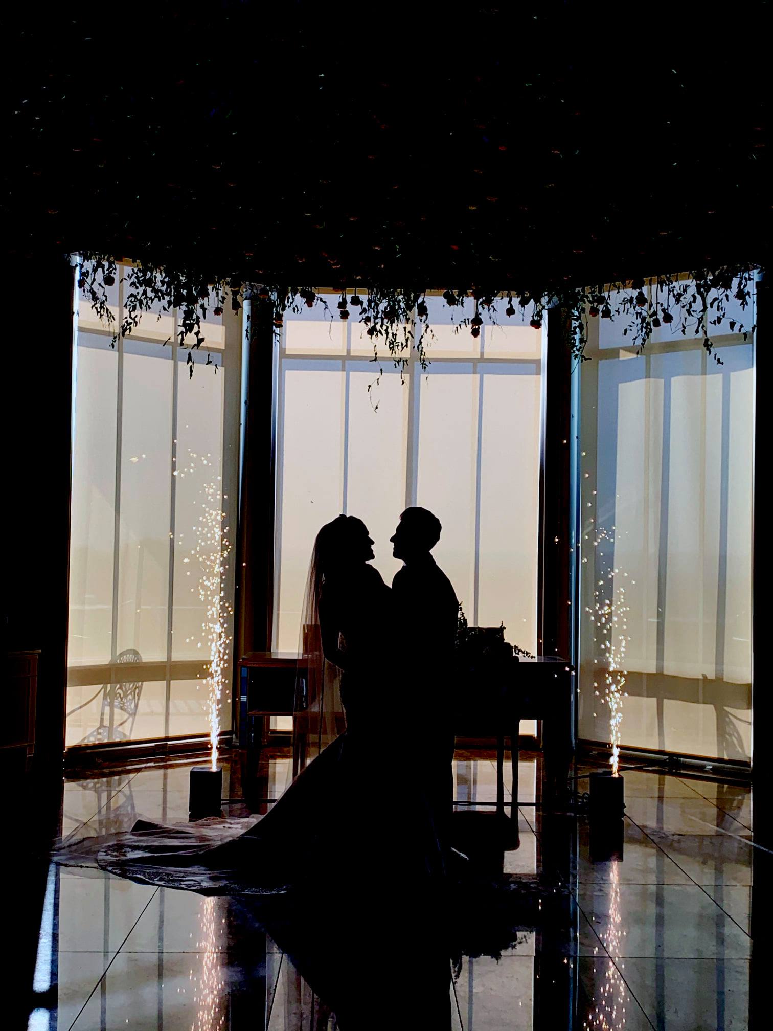 A silhouette of a bride and groom with fireworks.