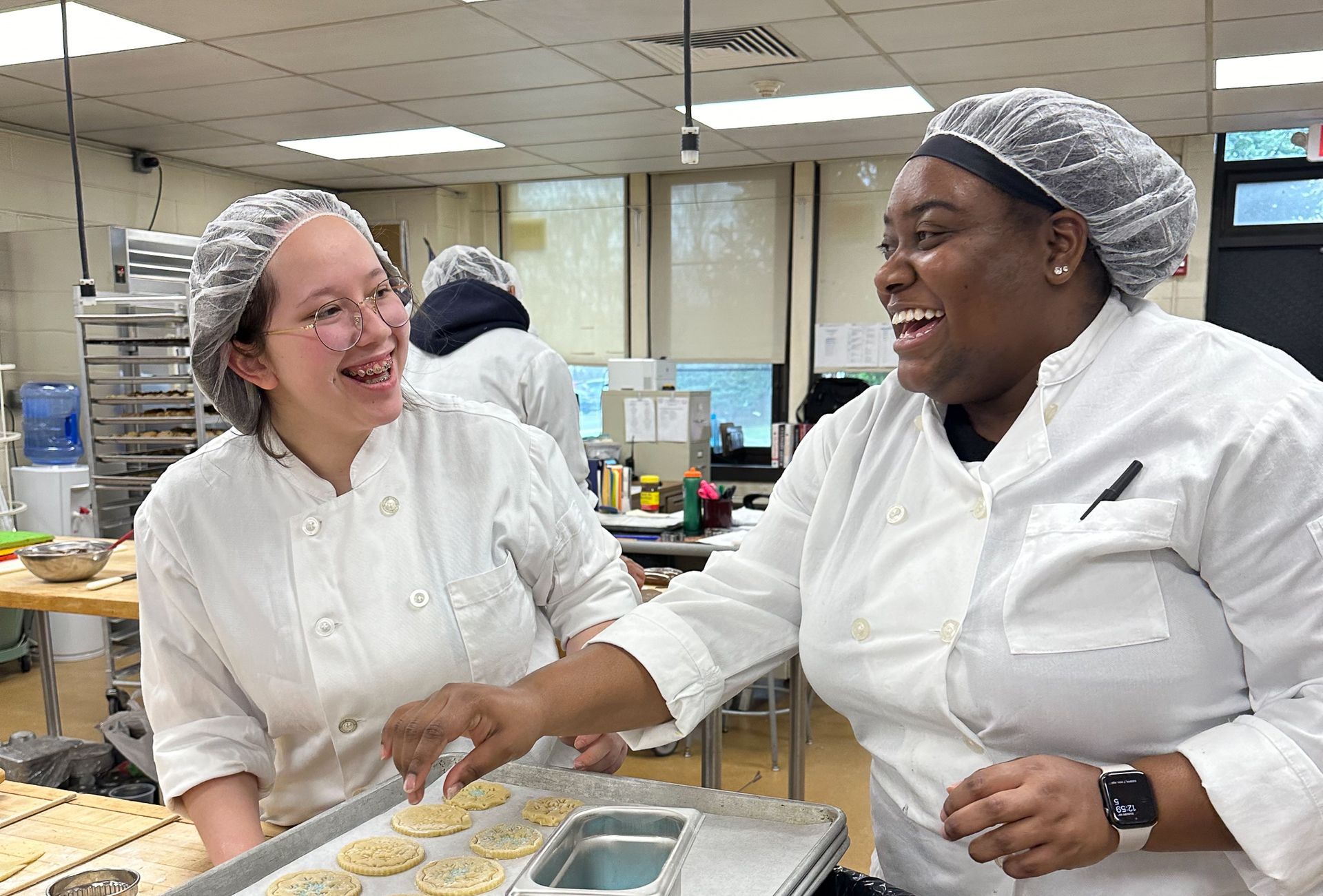 Two young ladies smiling as they bake.