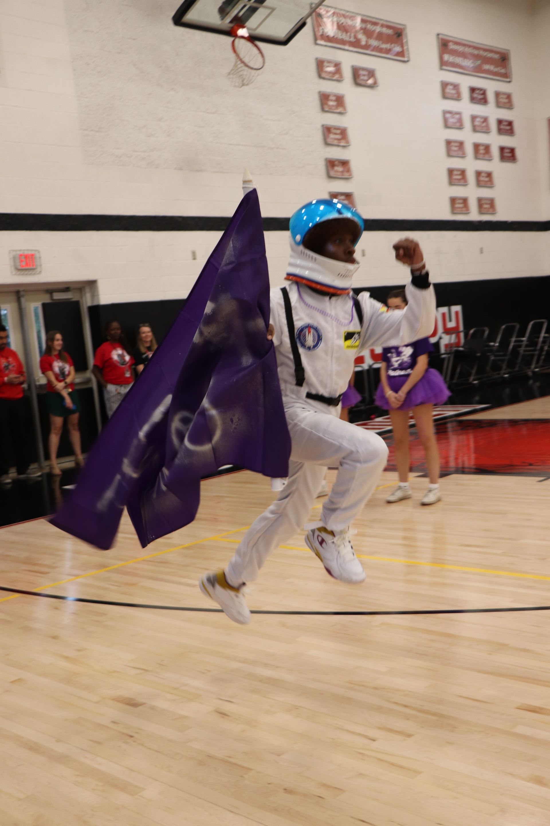 An astronaut holding a flag jumping in the air.