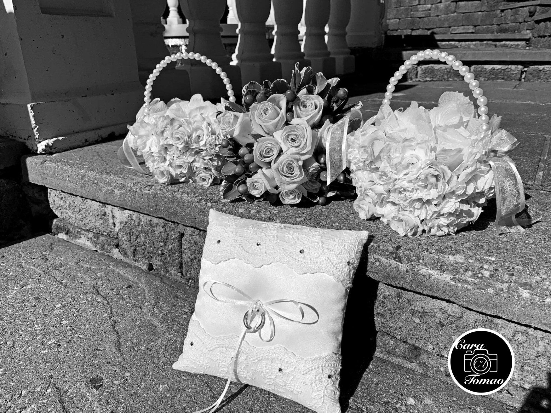 A black and white image of a ring bearer's pillow, flowers and baskets.