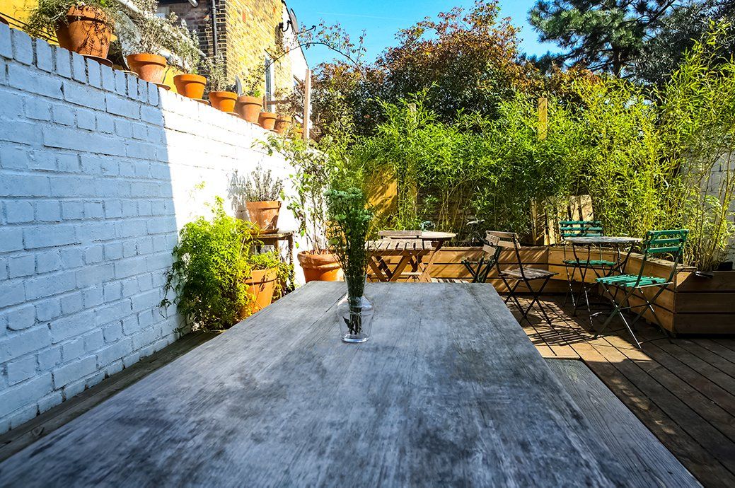 Photo of outdoor area of Le Merlin Bar in Clapton showing seating, plants, and painted white wall