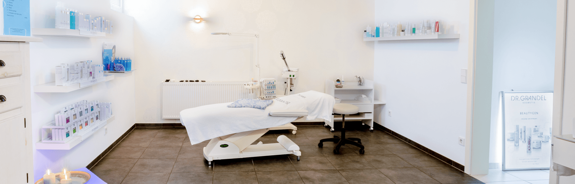 Hie befinden Sie sich im Behandlungsraum vom Kosmetik- und Wellnessinstitut Daniela Rathgeb Im hellen Behandlungsraum steht eine höhenverstellbare Behandlungsliege. Bei gedämpftem Licht kann man bei Kosmetik- und Wellnessinstitut Daniela Rathgeb entspannen