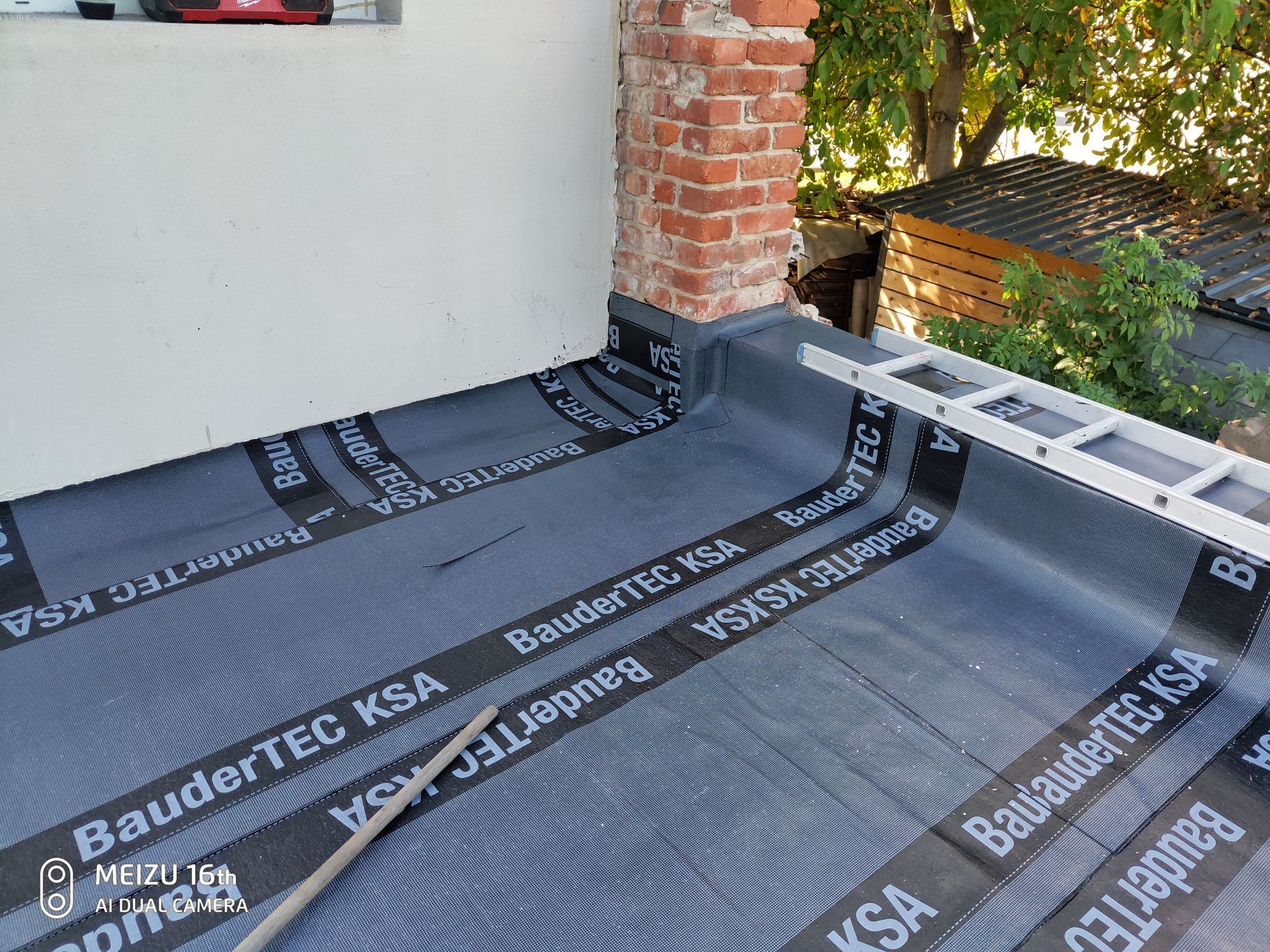 Flachdachabdichtung mit Anschluss an Wand und Schornstein mit Bitumenbahnen.