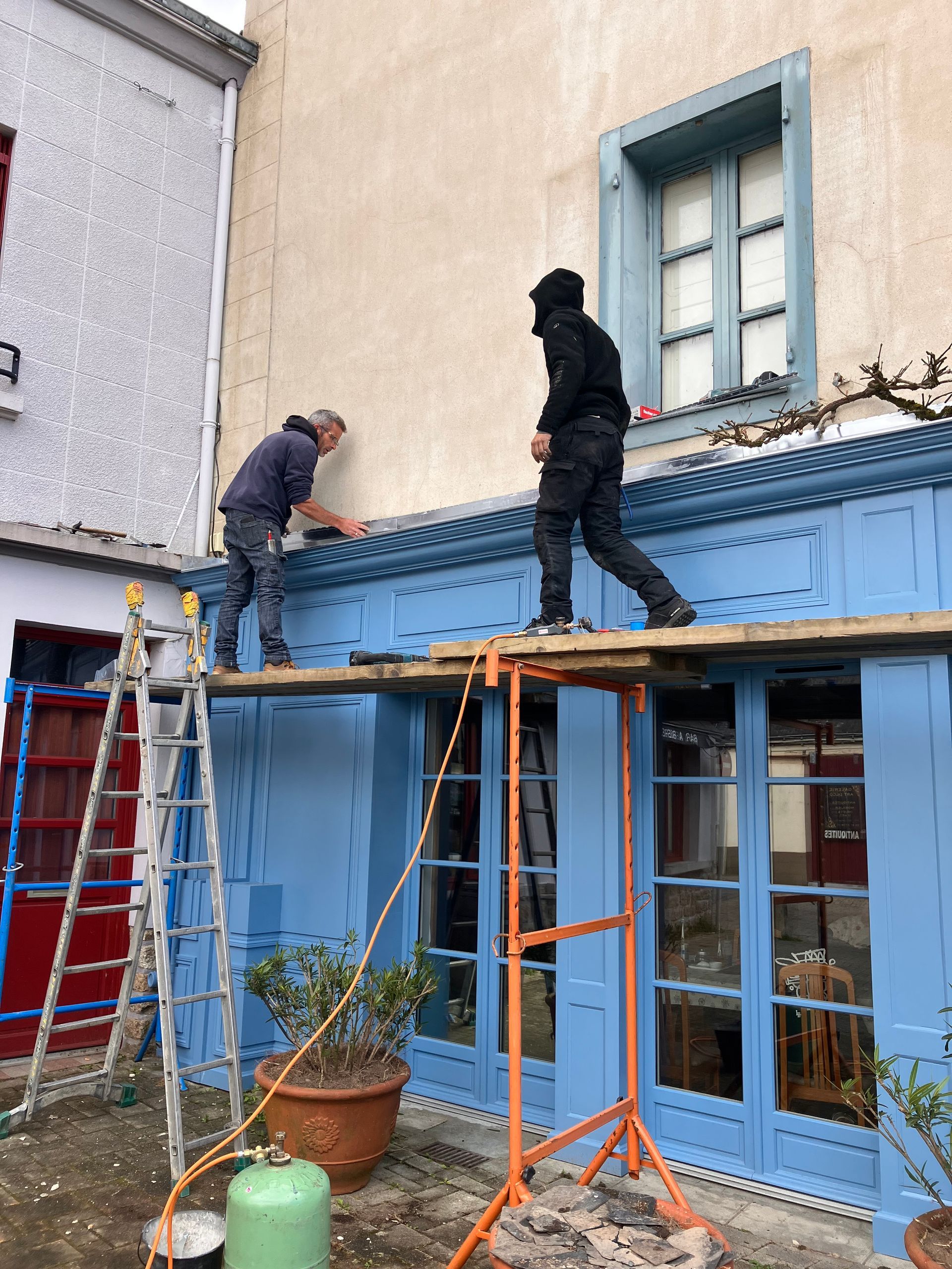 Artisans installant des menuiseries vitrées depuis l’intérieur du bâtiment