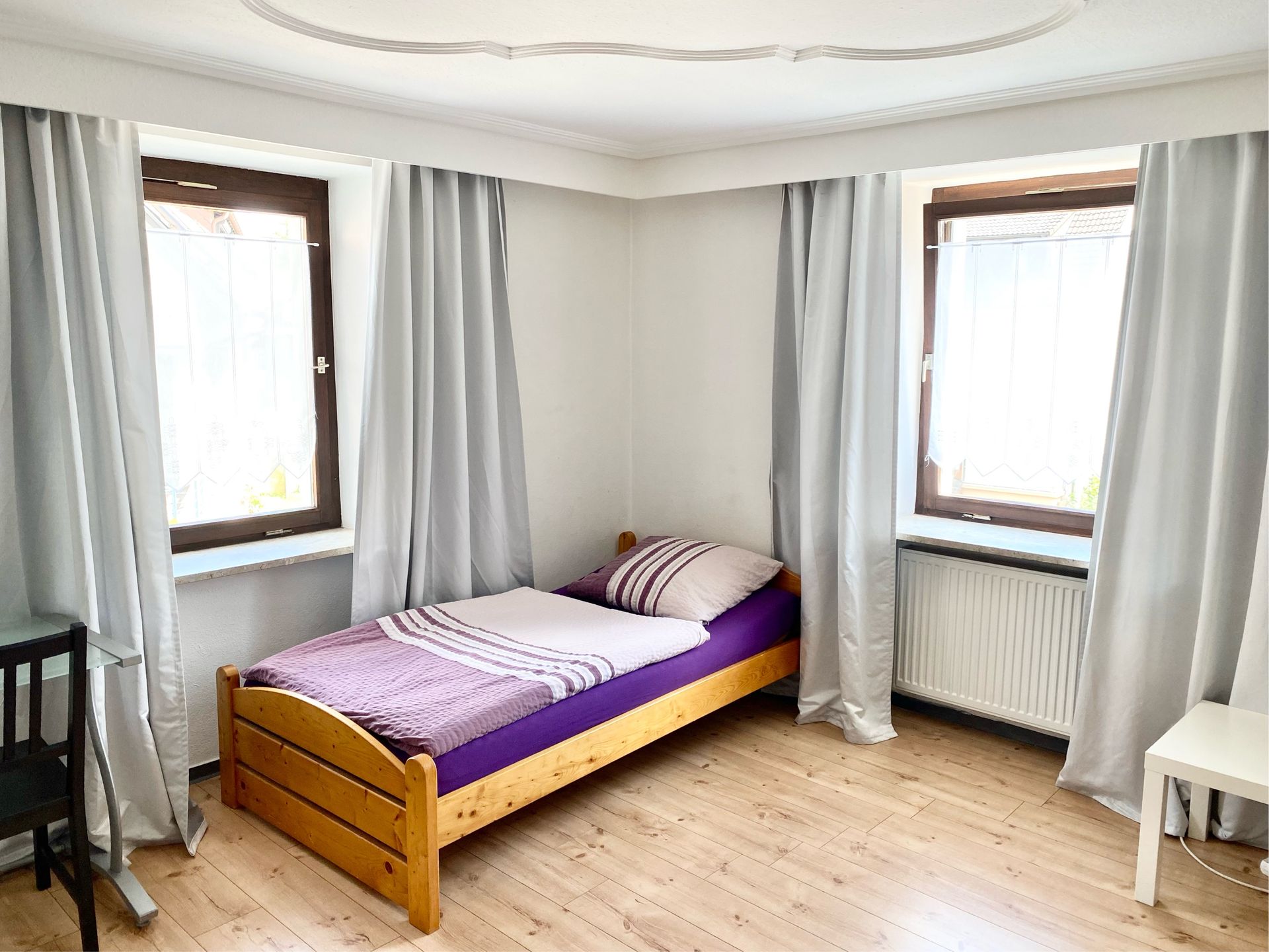 Möbliertes Einzelzimmer mit Bett, Schreibtisch, Kleiderschrank und TV.