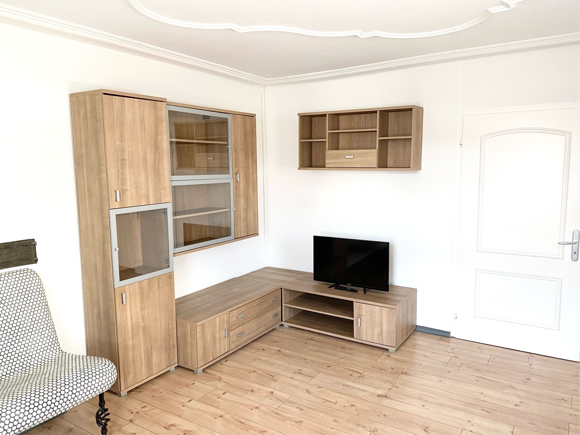 Möbliertes Einzelzimmer mit Bett, Schreibtisch, Kleiderschrank und TV.