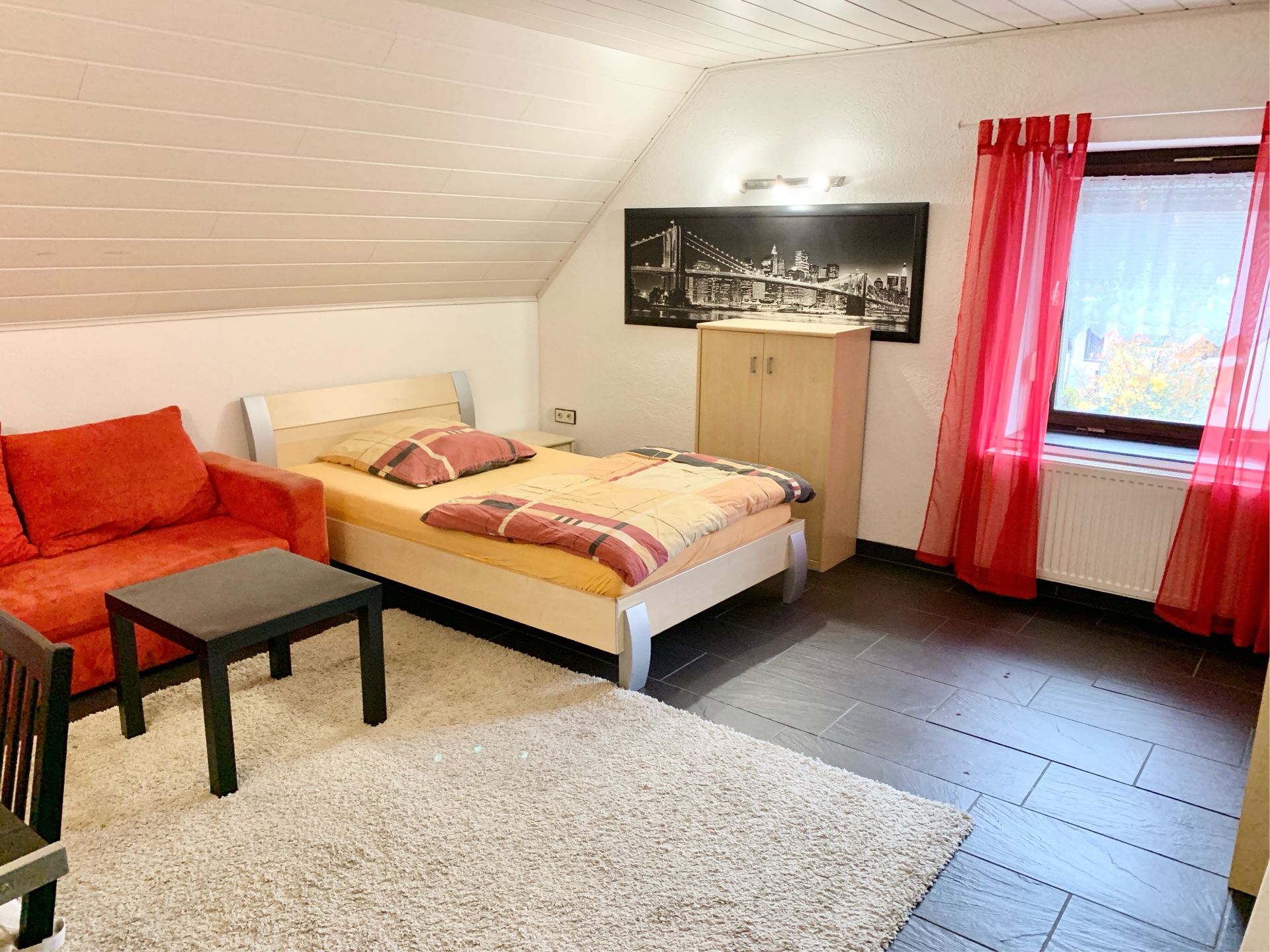 Beispielzimmer für Monteure mit Bett, Schreibtisch und Flachbildfernseher.