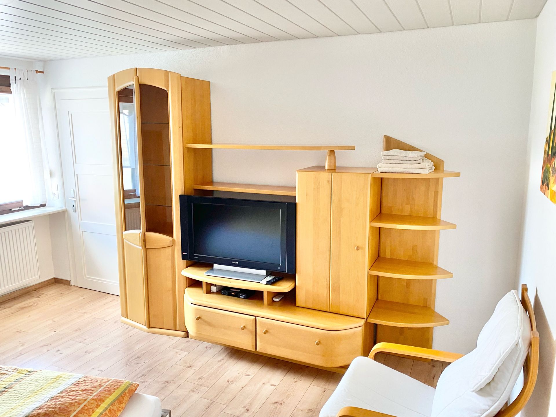 Möbliertes Einzelzimmer mit Bett, Schreibtisch, Kleiderschrank und TV.