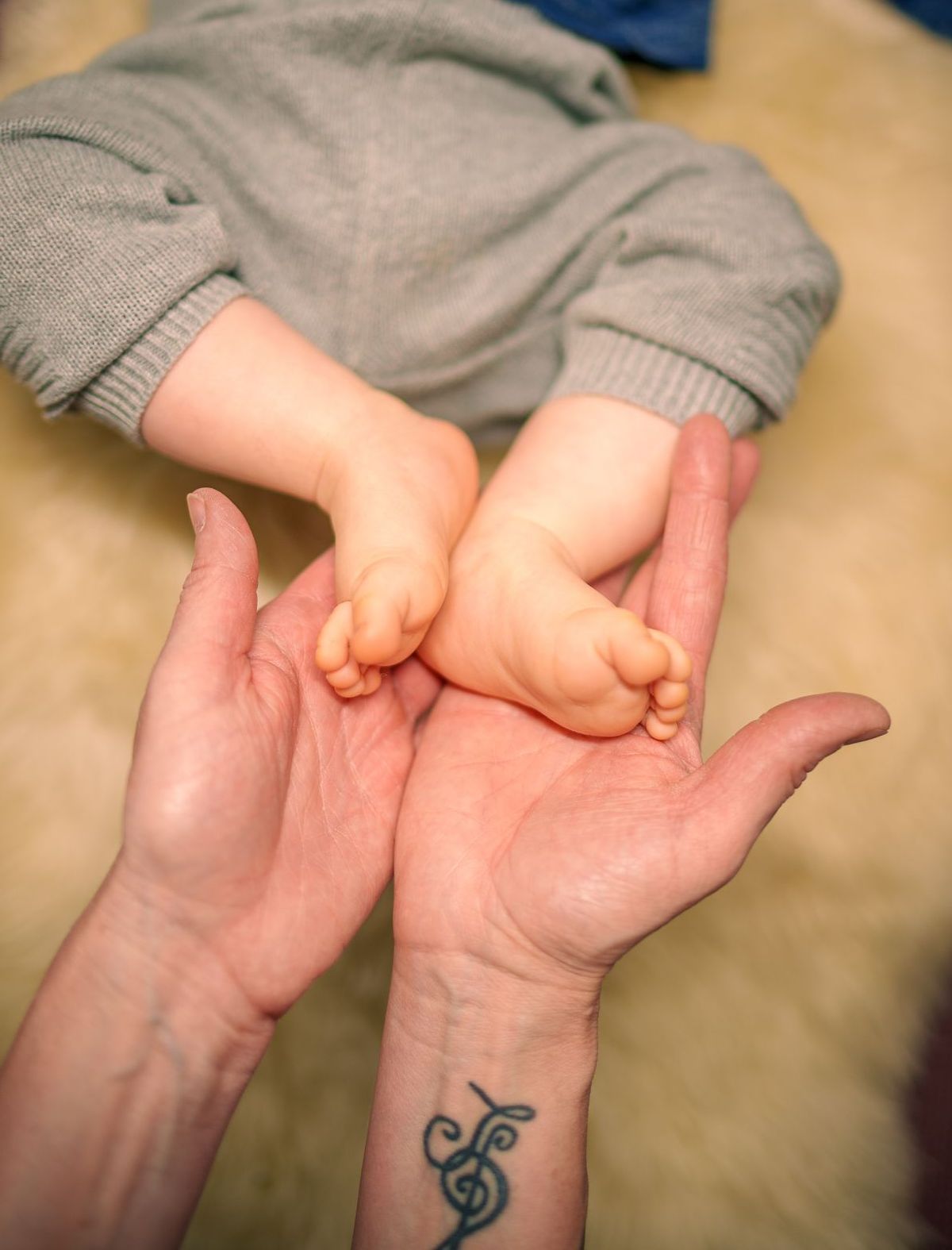 Babyfüße in Erwachsenen-Händen, Babymassage