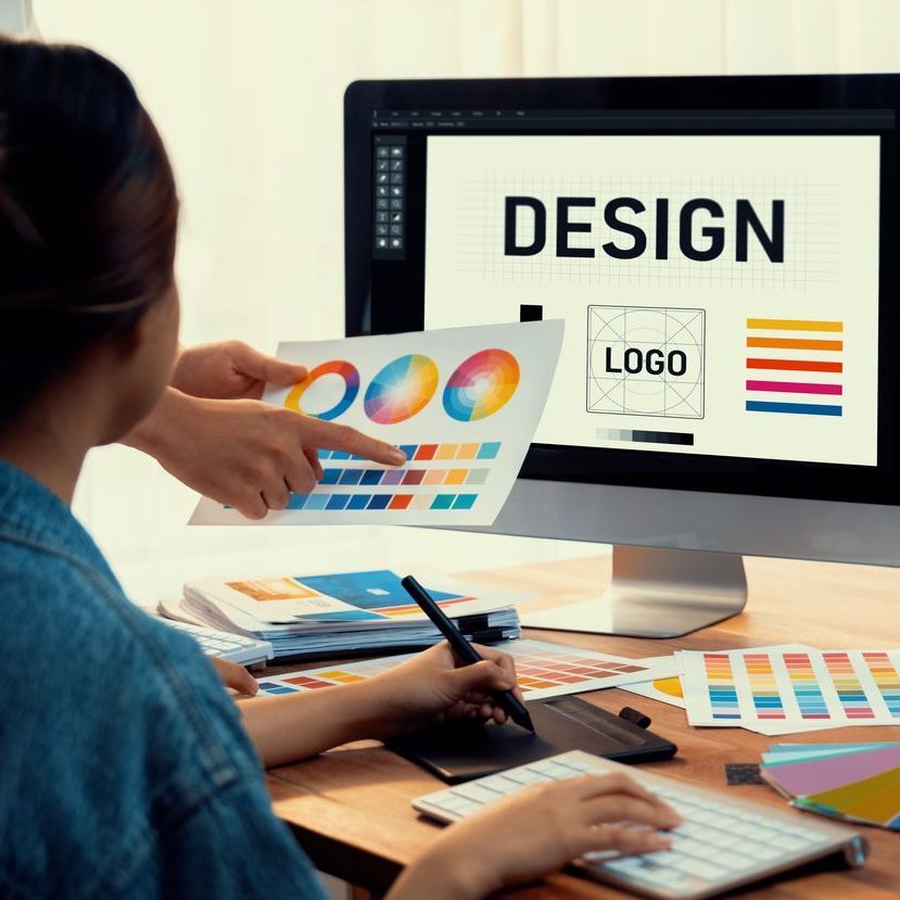 Grafikerin sitzt am Computer und gestaltet ein Logo