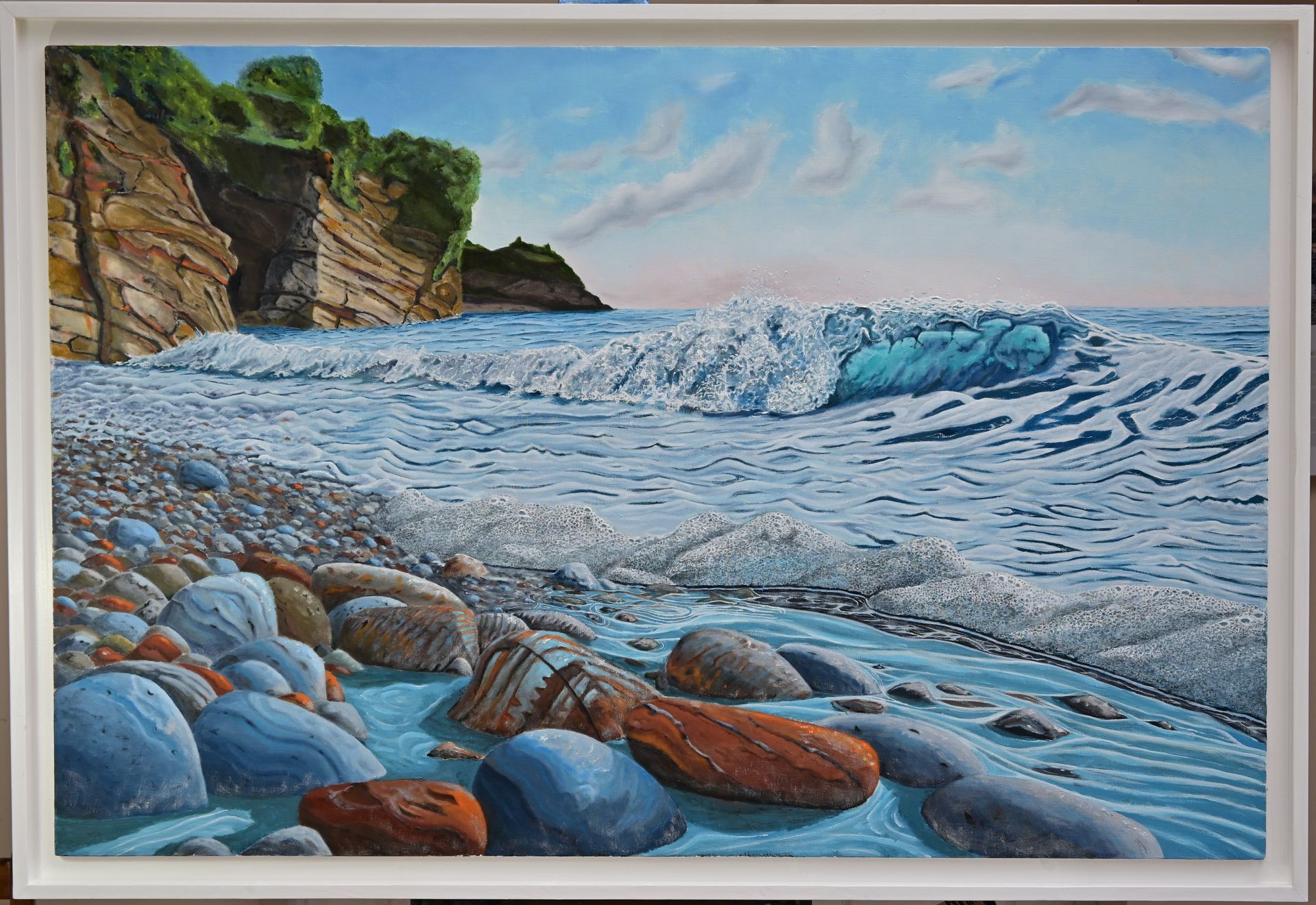 Oil painting by Mike Dudfield of colourful wave crashing onto a pebbly beach.