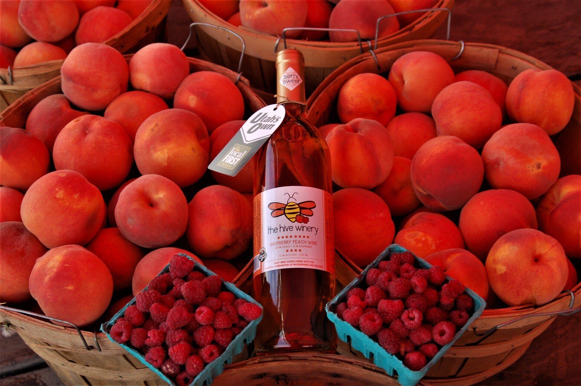 Raspberry Peach wine siting on fresh peaches with fresh raspberries.