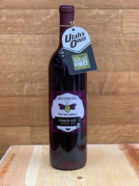 Single bottle of Pioneer Red Black Currant Wine in front of a wooden background.