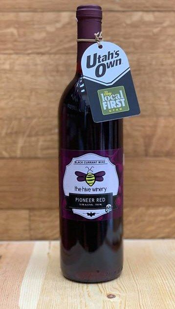 Single bottle of Pioneer Red Black Currant Wine in front of a wooden background.