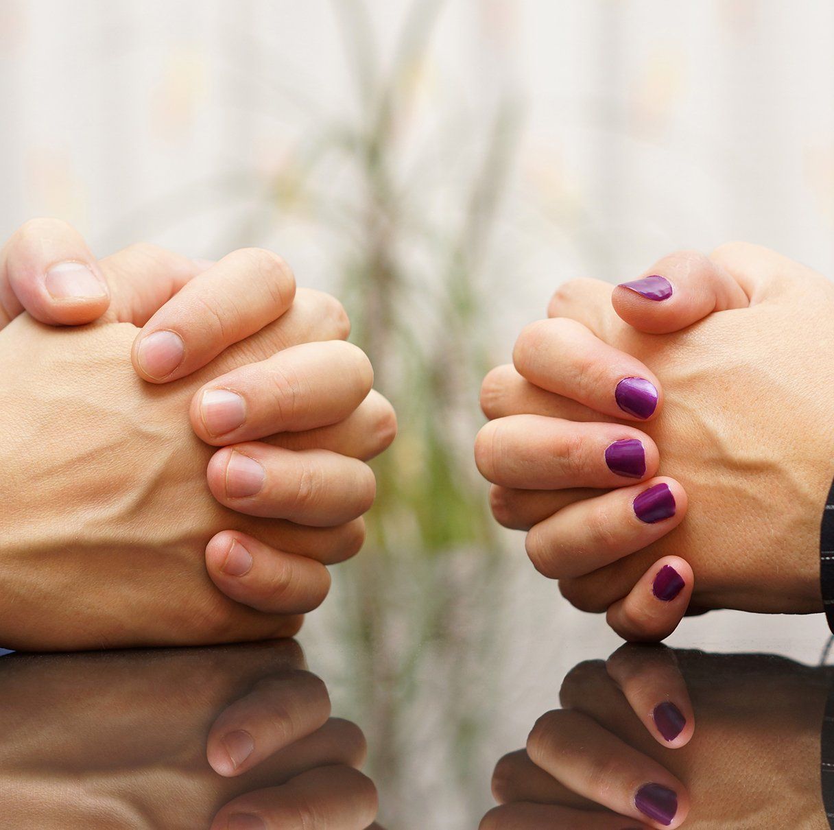 2 people at a table crossing their hands
