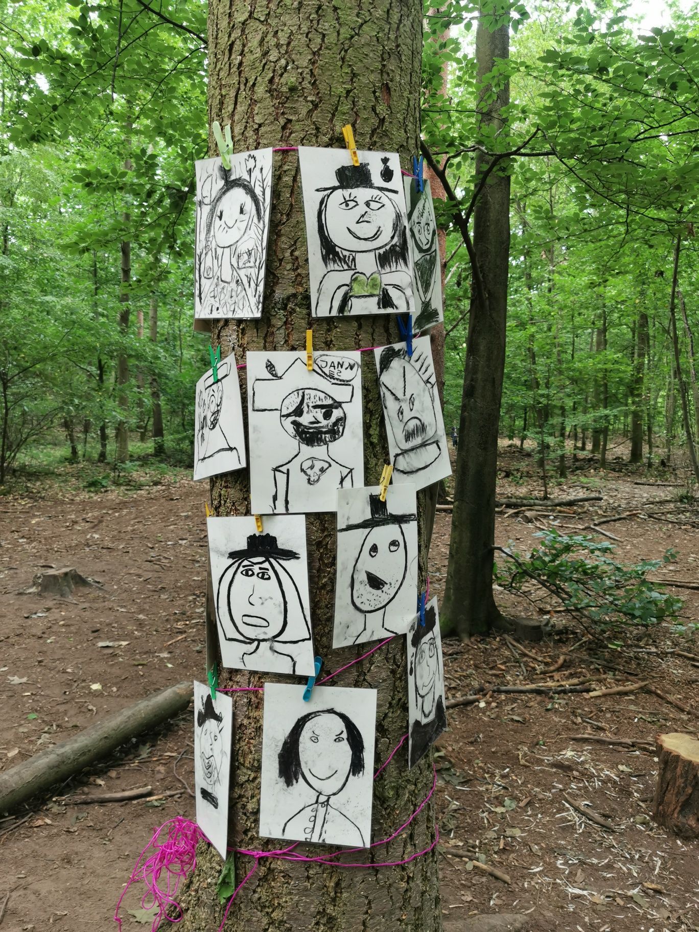 Waldpaedagogik Karlsruhe: Kohlezeichnungen von Kindern an einem Baum befestigt