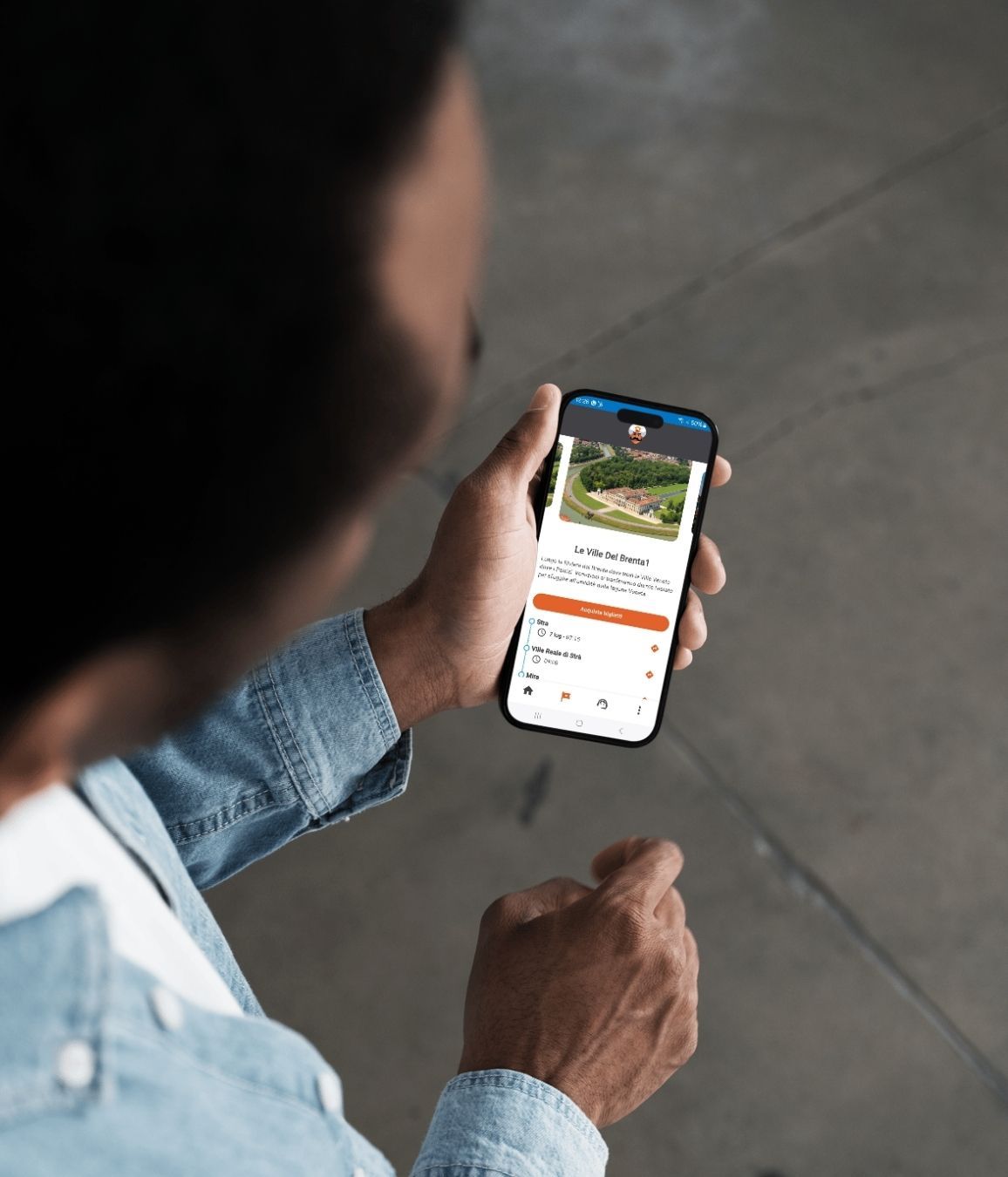 Persona con giacca di jeans che utilizza un’app di prenotazione viaggi su smartphone