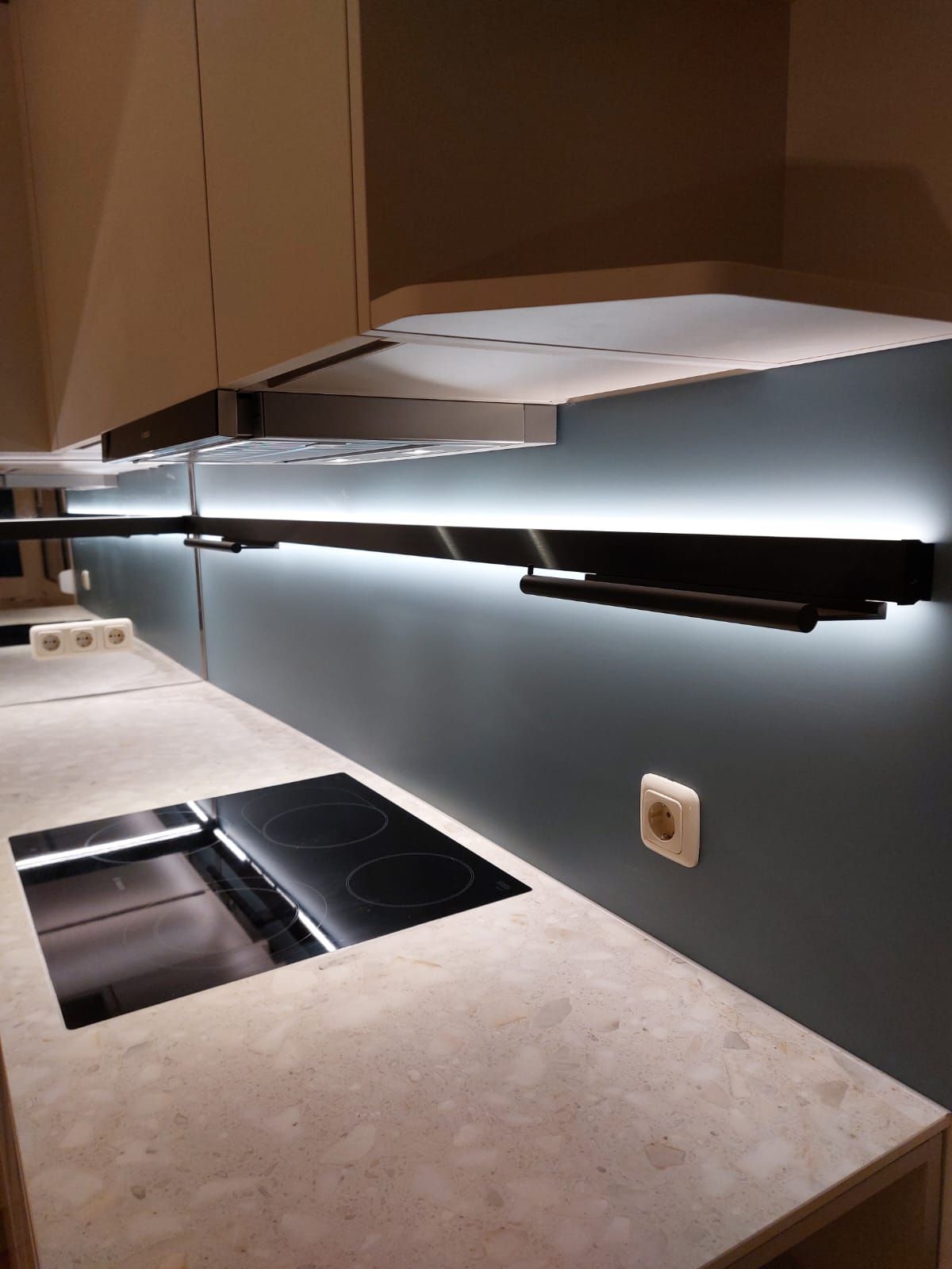 Schwarzes Schienensystem mit magnetischer Messerfläche und modernen Steckdosenmodulen.