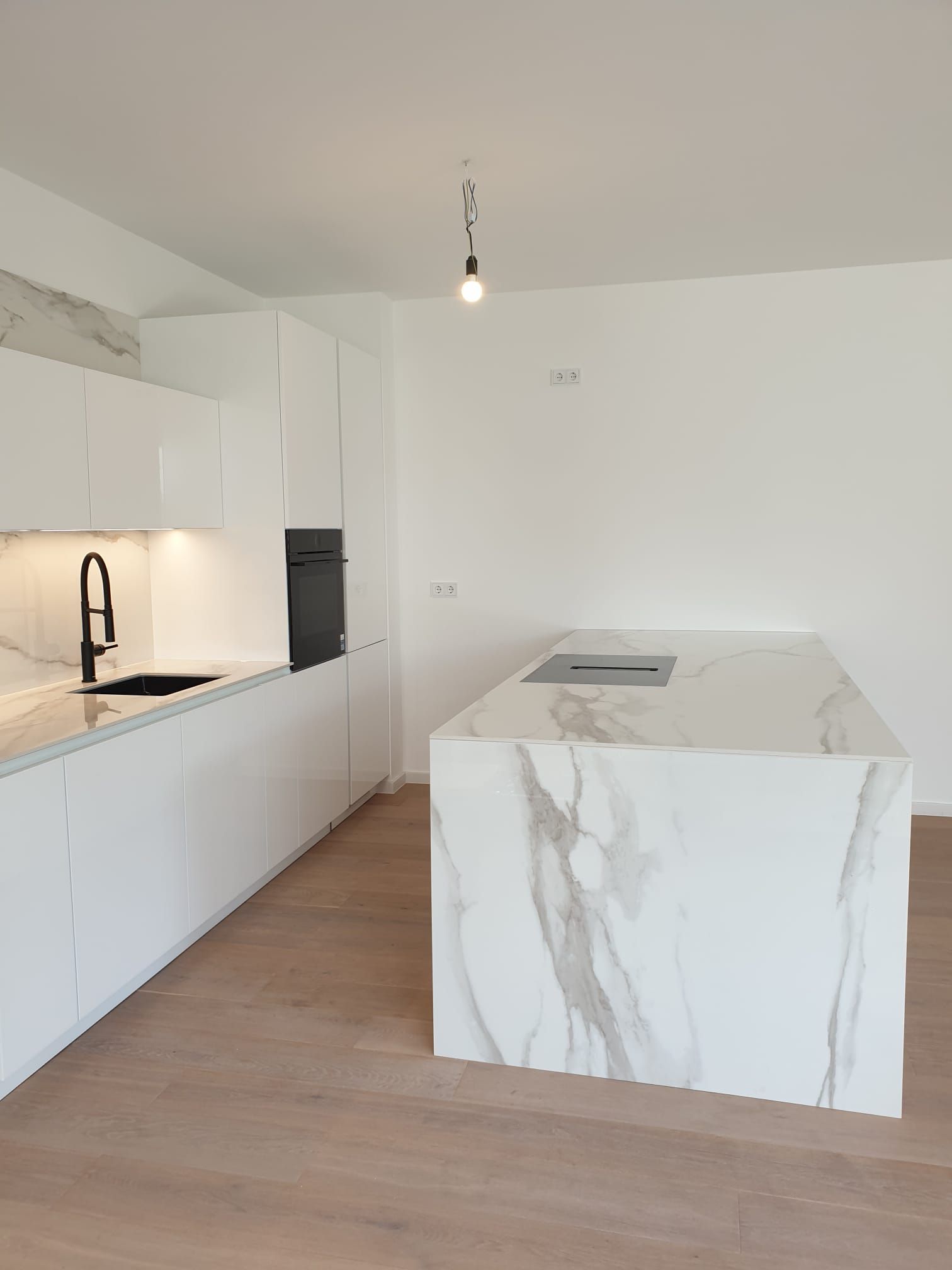 Entdecken Sie das perfekte Gleichgewicht zwischen Ästhetik und Funktionalität in unserer Ballerina Küche, die mit einer einladenden Sitzmöglichkeit an der Halbinsel sowie stilvollen Smartglas Hochglanz Fronten und marmorierten Keramik-Arbeitsplatten ausgestattet ist.